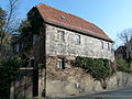 Wohnhaus mit Stützmauer und Toreinfahrt in offener Bebauung