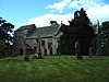 A stone church seen from the southeast with an elongated squat west tower surmounted by a saddleback roof