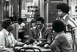 From TV's What's Happening!! (1977). Seated, L-R: Fred Berry, Ernest Lee Thomas, and Haywood Nelson (back to camera). Standing: Shirley Hemphill. What's Happening partial cast 1977.JPG