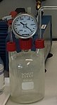 En Woulfe-flaska skyddar den manometer som monterats på den mellersta halsen för att mäta undertrycket vid ett experiment för att visa ångtryckets temperaturberoende.