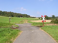 Unsecured crossing indicated by a sign. This local railway line is in rural Germany, in the Taunus mountains.