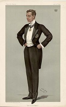 Old colored drawing of a formally dressed young man in a tuxedo with white tie and waistcoat, medallions from one honor hanging from a ribbon around his neck and another on the front of his open coat, his hands on his hips, facing 1/4 to his right