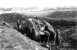 Német katonák egy kilőtt Mark IV-es harckocsit szemlélnek.