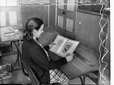 Girl reading a book featuring the title 'The Children's Hour' and a photograph of a Hippopotamus in Thebarton Primary School, South Australia (1945).