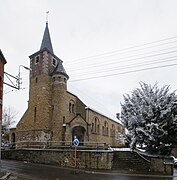Édifice religieux en pierre de style néo-roman sous la neige.