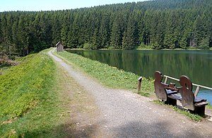 Damm und Wasserfläche des Neuen Grumbacher Teiches mit einer Bank des Liebesbankweges