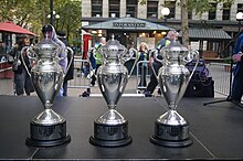 Three trophies placed in a line on a stage.