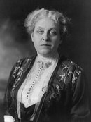 Middle-aged woman with short hair, in white blouse and dark jacket