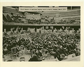 Fotografía en blanco y negro del interior del Cirque de Paris. Varias decenas de militares están sentados en sillas plegables en el centro de la pista, otros en los palcos de la planta baja, y otros en las gradas de la primera planta.