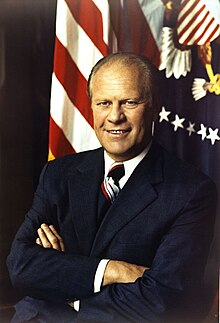 President Gerald Ford, arms folded, in front of a United States Flag and the Presidential seal.