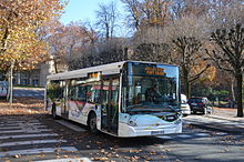 Photographie en couleurs d'un bus circulant sur une route en ville.