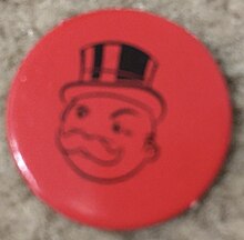 A red cardboard coin with Mr. Monopoly's face on it.