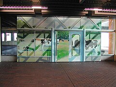 A mural of a fake doorway with cows grazing in a field