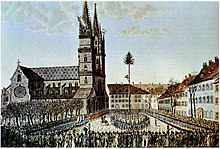 Die Verbrüderungsfeier auf dem Münsterplatz in Basel vom 22. Januar 1798 in einer zeitgenössischen kolorierten Radierung. In der Mitte des Platzes steht der Freiheitsbaum als Zeichen der Rechtsgleichheit. Kolorierte Radierung