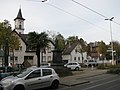 der Turm der Dreifaltigkeitskirche und rechts das hellbraun geklinkerte Pfarrhaus