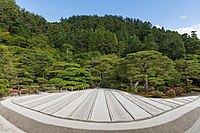 Jardin zen de sable sec à longues rayures beiges, vu de face avec une impression de perspective centrale, des fleurs et des arbres en arrière-plan, un jour ensoleillé au temple bouddhiste zen Higashiyama Jisho-ji, du Ginkaku-ji, le temple du Pavillon d'argent (juin 2019).