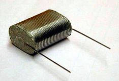 Flatted winding of a film capacitor with the view onto the collateral metal contact layer (schoopage) and the soldered terminals