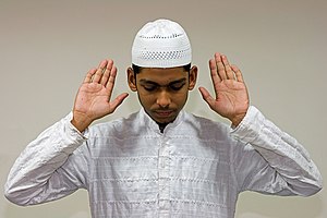 English: A Muslim raises his hands in Takbir, ...
