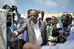 Official tastes the water of a new well in front of journalists in Mogadishu, Somalia, 2014.