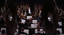 Bernard Herrmann conducting the orchestra in a scene from Hitchcock's The Man Who Knew Too Much (1956) Alfred Hitchcock The Man Who Know Too Much 1956 trailer.png