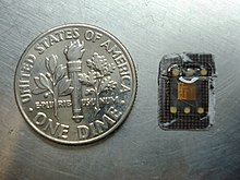 The memory chip from a micro-SIM card without the plastic backing plate, next to a US dime, which is approx. 18 mm in diameter Disassembled SIM Card Film.JPG
