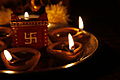 Lampade a olio e candela con svastica per la festa di Divali.