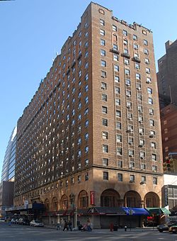 Высокое прямолинейное здание из коричневого кирпича на углу городской улицы с равномерно расположенными окнами и арками вдоль уровня улицы.