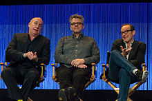 Three men sitting, facing the camera. Jeph Loeb, on the left and Jeffery Bell, middle, have their hands touching, with Clark Gregg on the right with his leg crossed.