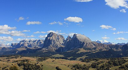 Langkofel (links) und Plattkofel (rechts) von Nordwesten. Im Hintergrund links die auffällig terrassierte Sellagruppe und rechts der wolkenbehangene Gipfel der Marmolata