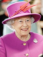 A smiling woman wearing a purple dress and matching hat