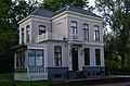 Statig neoclassicistische villa met onregelmatig verloop in fraaie tuin.