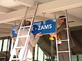 Die Bürgermeister von Landeck und Zams bringen gemeinsam das neue Schild für den umbenannten Bahnhof an