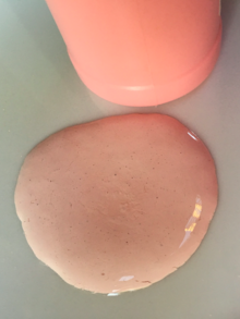 一灘粉紅色的薄乳液，旁邊是一個粉紅色的塑料瓶