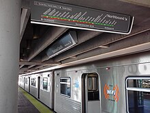 A metro train sits beside a station platform with its doors open. A map of the metro system hangs from the roof of the station.