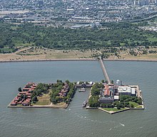 Seen from east. From left to right: contagious diseases ward; lawn; hospital; ferry basin; main building, kitchen, dormitory, and immigration building Ellis Island Complex.jpg