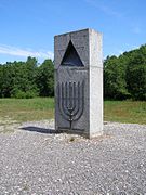 Un triángulo gris (incoloro para marcar un triángulo xenerico, indefinido) no memorial das vítimas xudías de Klooga