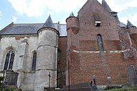 À gauche, le chœur en pierre calcaire, partie la plus ancienne de l'église datant du début du XVIe siècle; à droite la partie fortifiée en brique a été construite au XVIIe siècle.