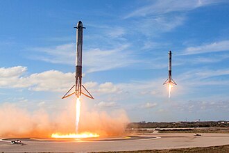 Falcon Heavy side boosters landing during 2018 demonstration mission. Falcon Heavy Side Boosters landing on LZ1 and LZ2 - 2018 (25254688767).jpg