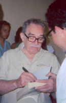 Седовласый мужчина с усами и очками стоит во время раздачи автографов.