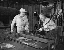 Photo en noir et blanc de deux personnes travaillant dans une fonderie de plomb.