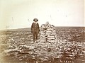 "Photograph of an expedition member standing beside an Inuit cairn at the east end of Aberdeen Lake, Nunavut. The photograph was taken by J.B. Tyrrell on the 1893 expedition to the barren lands"