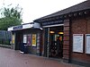A red-bricked building with a rectangular, dark blue sign reading "NORTH ACTON STATION" in white letters all under a white sky
