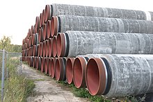 Stack of pipes that make up the Nord Stream 2 pipeline, made from steel with a concrete casing Stack of pipes North Stream 2.jpg