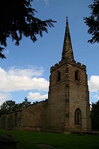 In the foreground is the tower of a stone church with a recessed spire, and the body of the church extends beyond it