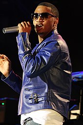 A man wearing a blue jacket holding a microphone