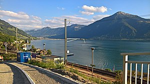 Shelter next to single-track and platform with lake and mountains in the background