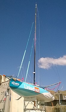 Voilier bleu et blanc sur un ber, vu en entier (sauf le bas de la quille) en contre-plongée.