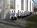 Una fila di ministranti durante una processione cattolica. Si nota il crocifero che regge la croce astile