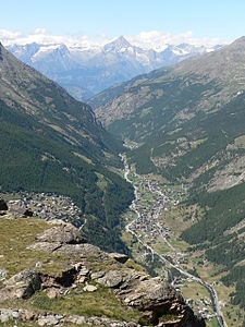 Saastal mit Saas-Fee (links) und Saas-Grund (Bildmitte). Im Hintergrund die schneebedeckten Berner Alpen.