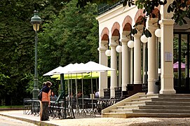 Photographie en couleurs de la terrasse d'un café-restaurant agrémentée de parasols vert pomme, par temps ensoleillé au printemps